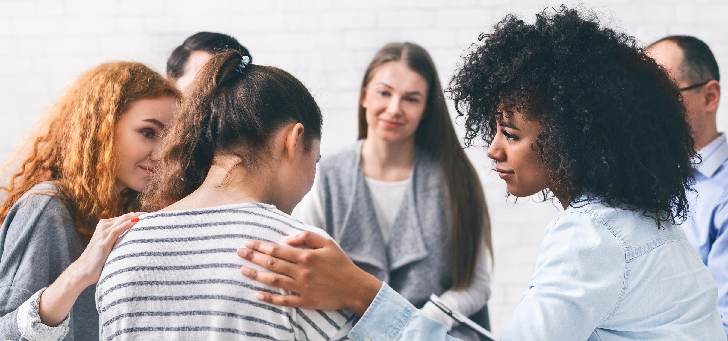 Support group patients comforting woman at therapy session